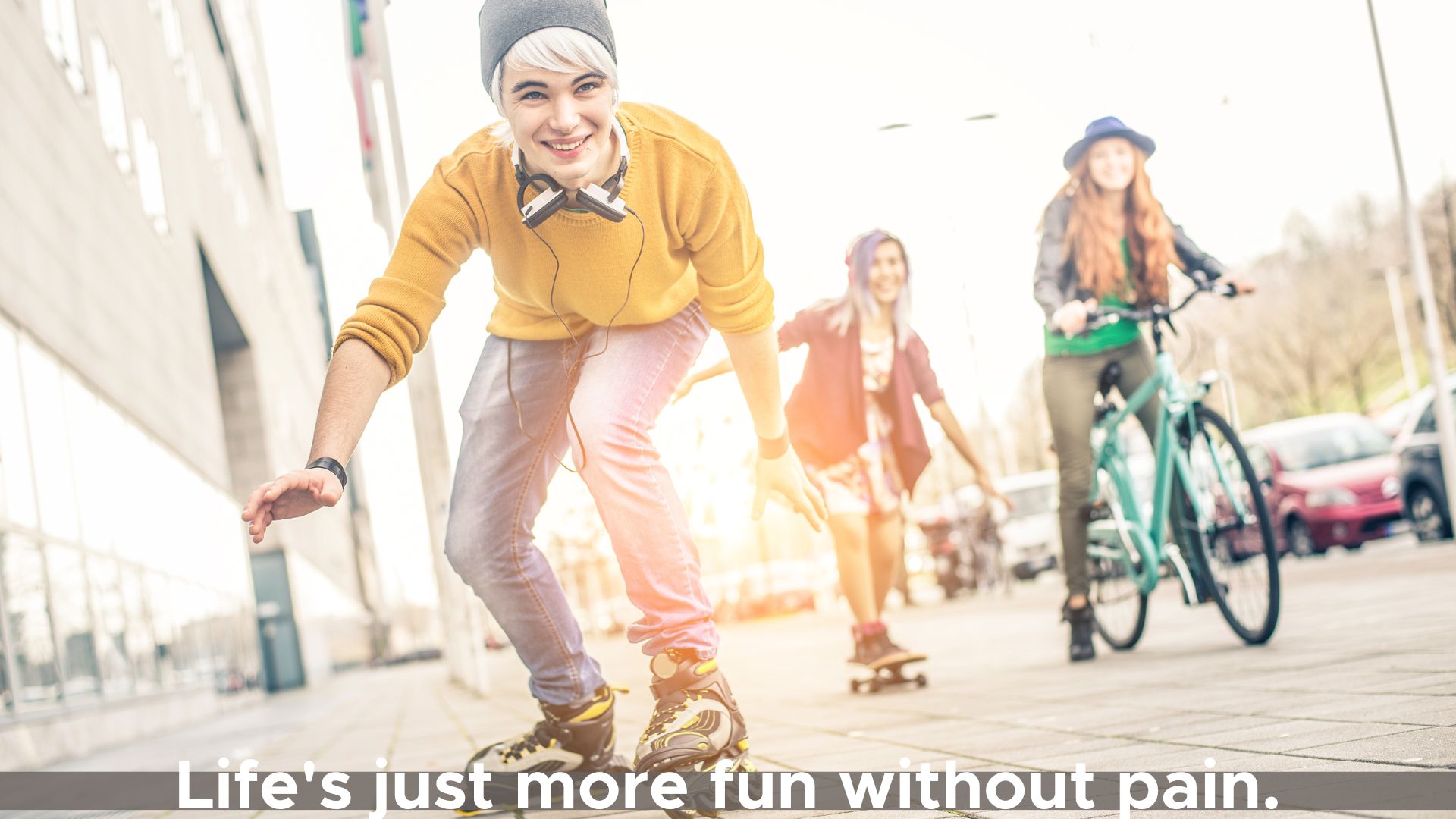 Three teens having fun riding bikes and skates on a sidewalk