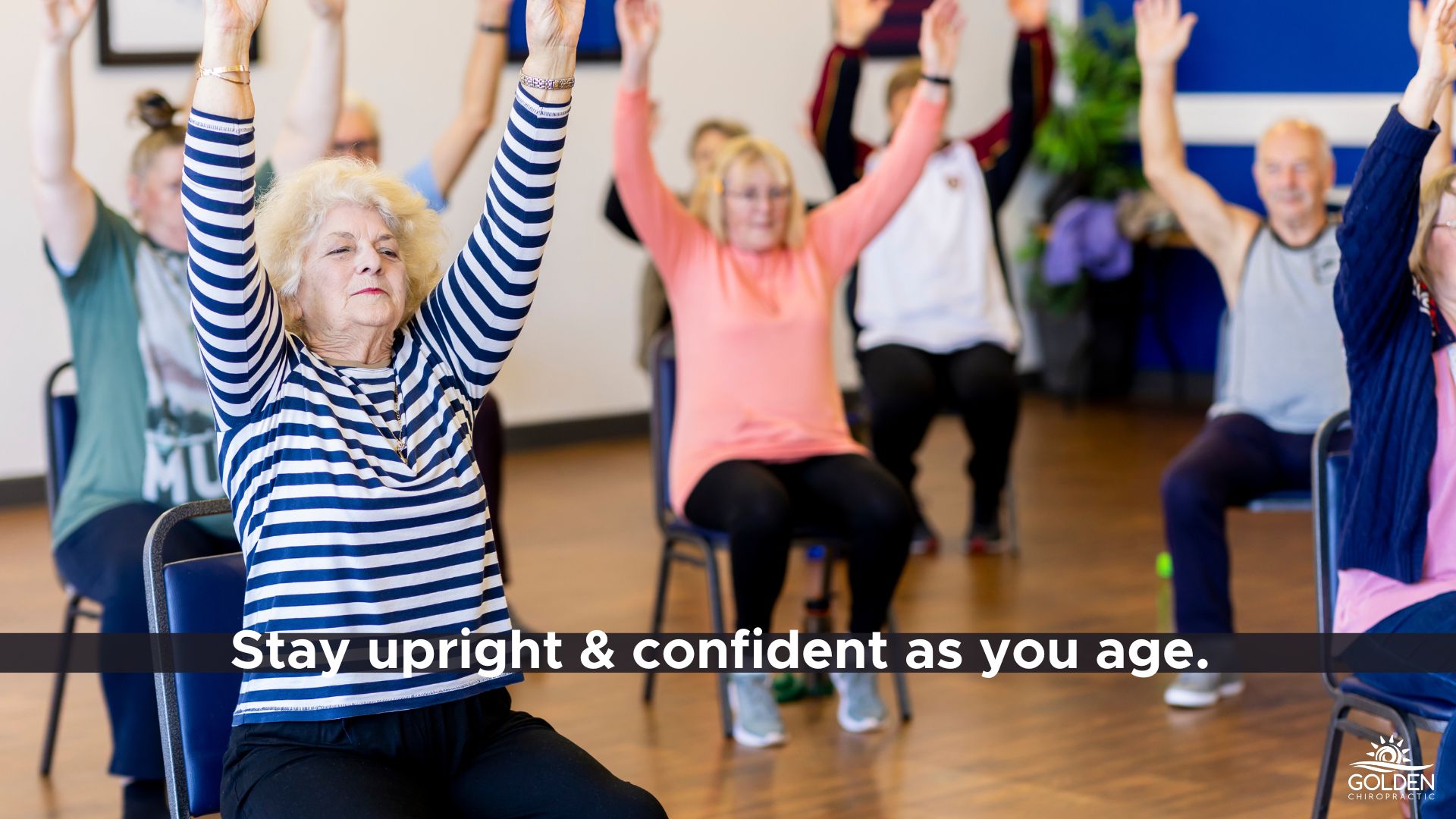 Senior citizens in a chair exercise class raising their arms above their heads