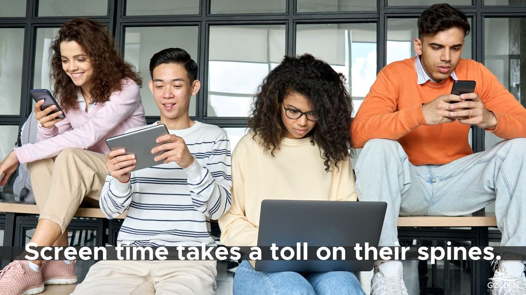 4 teens leaning over four different devices while seated together