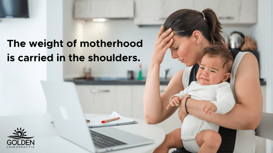 Exhausted mom clutching her forehead and holding a crying baby in front of a computer