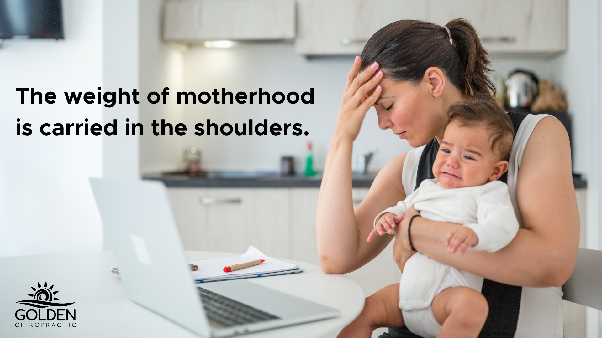 Exhausted mom clutching her forehead and holding a crying baby in front of a computer