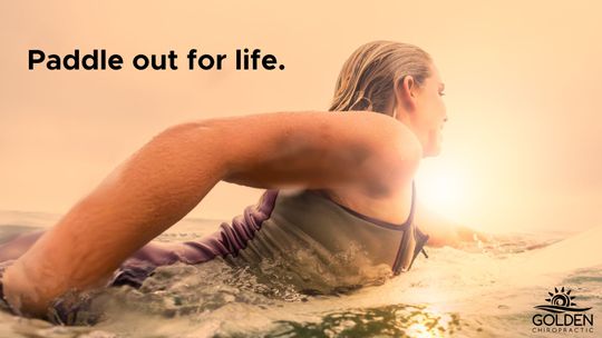 woman prone paddling in the ocean on a surfboard