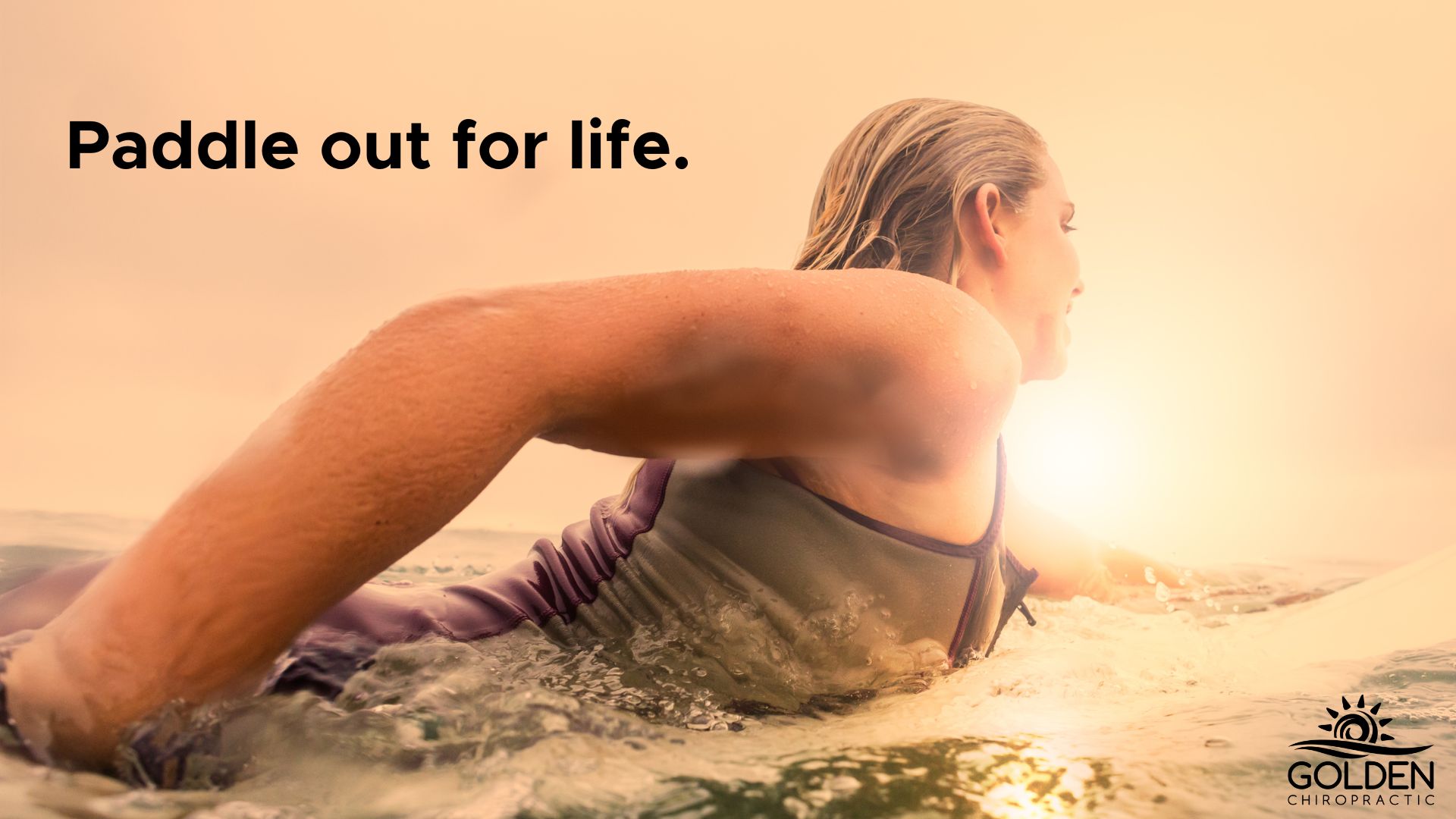 woman prone paddling in the ocean on a surfboard