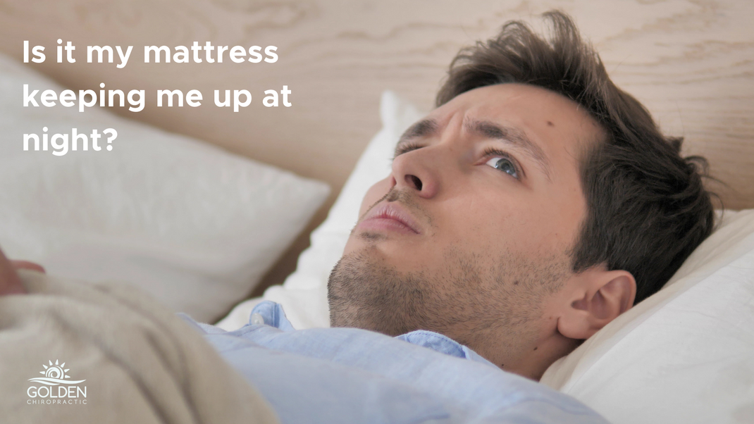 man laying uncomfortably in bed wondering if he needs a new mattress