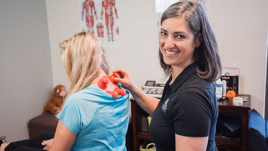 Dr Goldi applying rockpods to a patient's back neck and upper neck