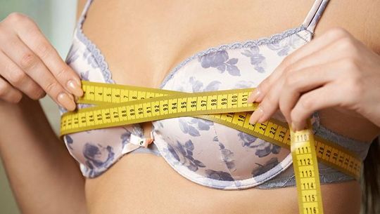 woman using measuring tape to measure bra size